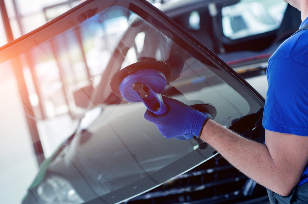 Automobilspezialist ersetzt die Windschutzscheibe eines Autos in einer Autowerkstatt.